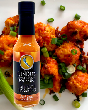 Gindo's Apricot Habanero hot sauce bottle with cauliflower wings on a white plate.