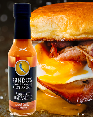 Bottle of Gindo's Apricot Habanero hot sauce with a breakfast sandwich in the background