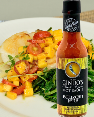 Bottle of Gindo's Belizean Jerk hot sauce with a salad in the background