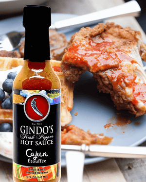 Gindo's Cajun Ecoutepe hot sauce bottle with fried chicken in the background