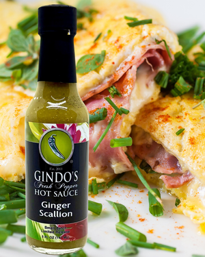 Bottle of Gindo's Ginger Scallion hot sauce with a eggs in the background
