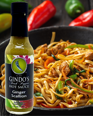 Gindo's Ginger Scallion hot sauce bottle with a dish of noodles and vegetables in the background