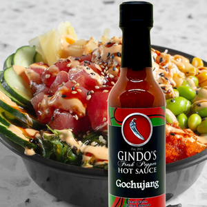 Bowl of poke with Gindo's Gochujang hot sauce on a gray surface