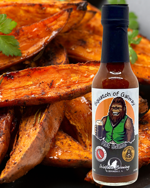 Bottle of Squatch of Galway hot sauce with roasted sweet potatoes in the background