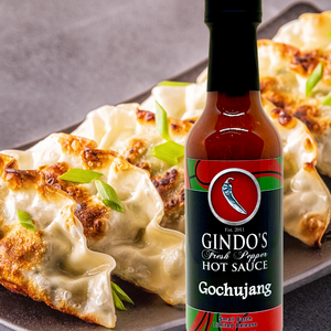 Bottle of Gindo's Gochujang hot sauce with dumplings in the background
