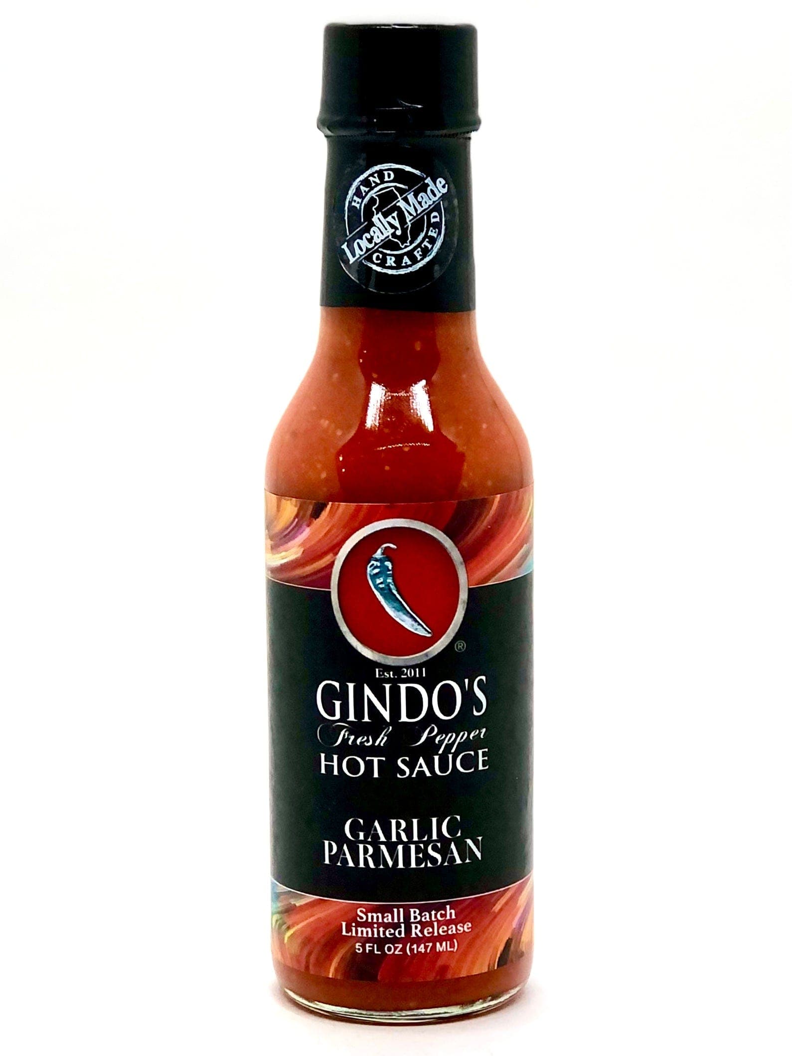 A bottle of Gindo's Hot Sauce with the label showing the brand name, product name, and an image of a chili pepper. The sauce appears to be medium-brown in color.